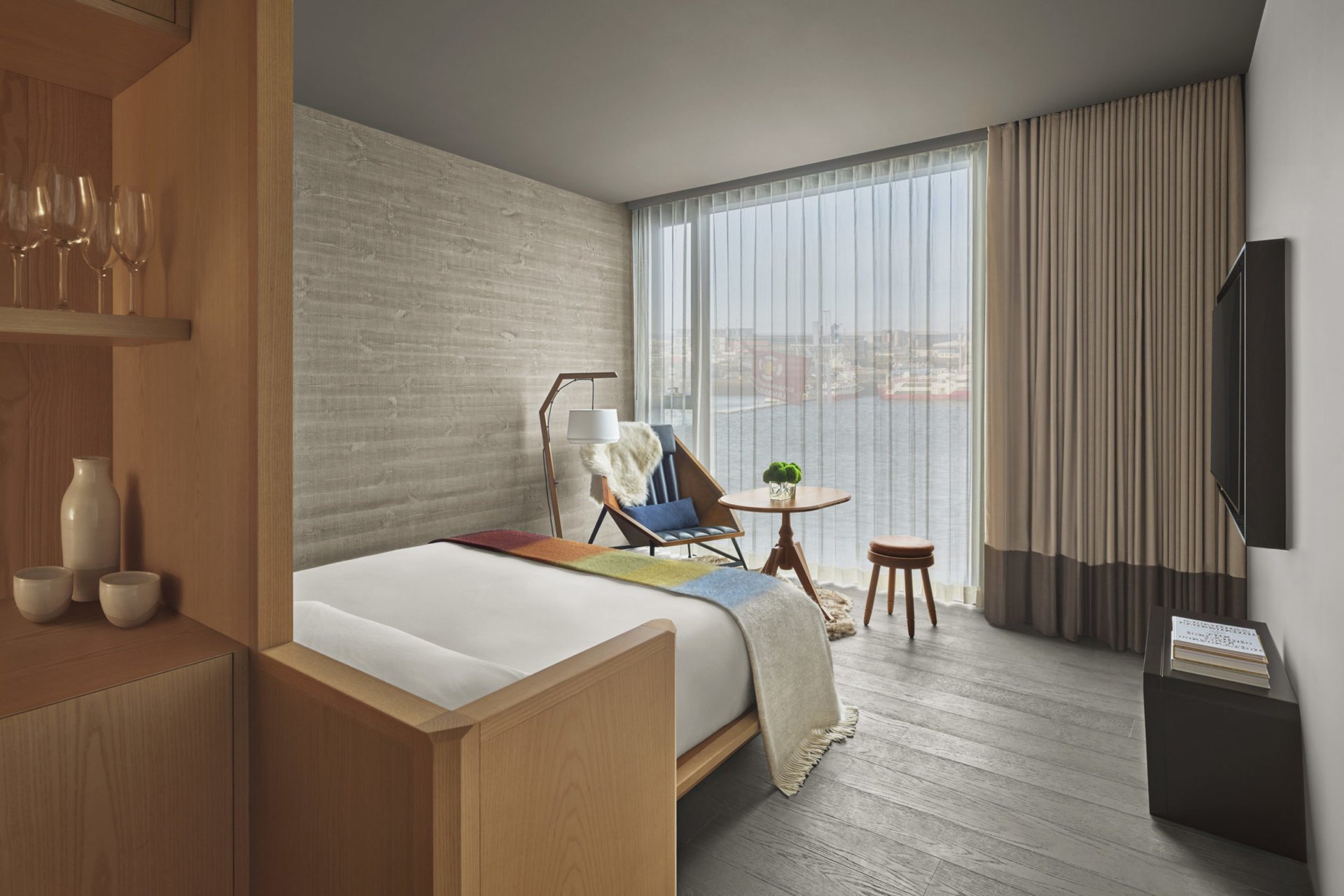 A guest room at The Reykjavik EDITION, with wool throws and the harbour through the window